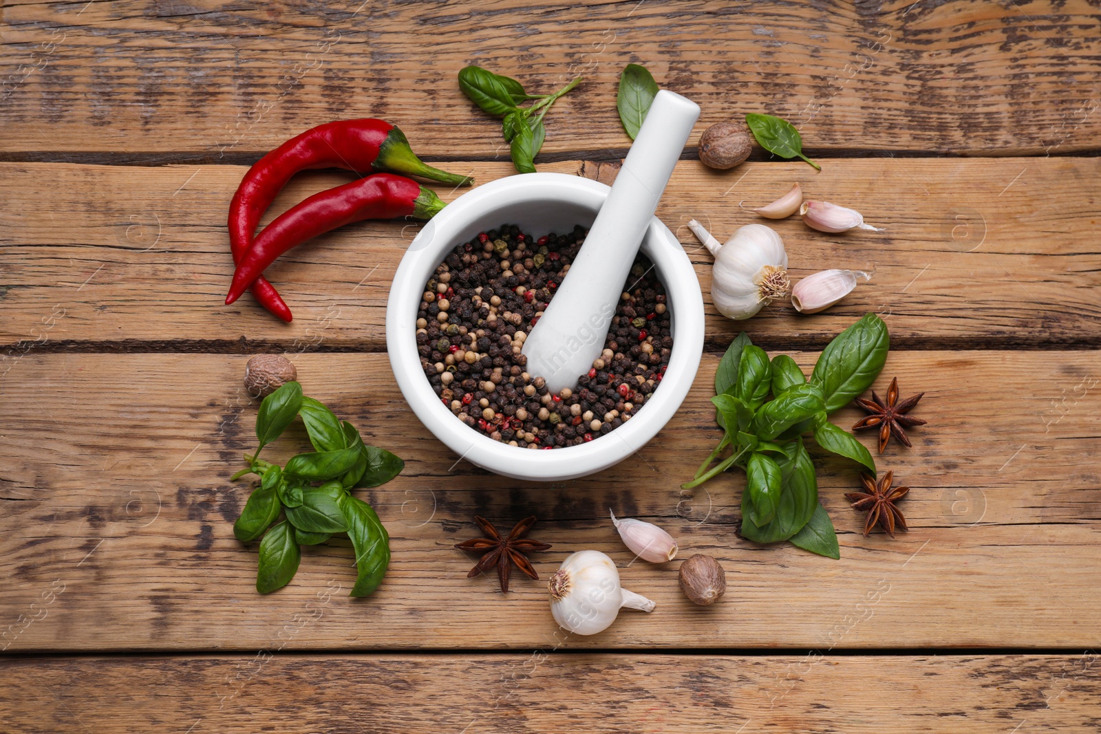 Photo of Mortar with pestle and different spices on wooden table, flat lay