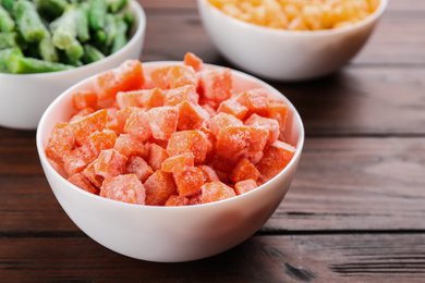 Photo of Different frozen vegetables on wooden table, closeup