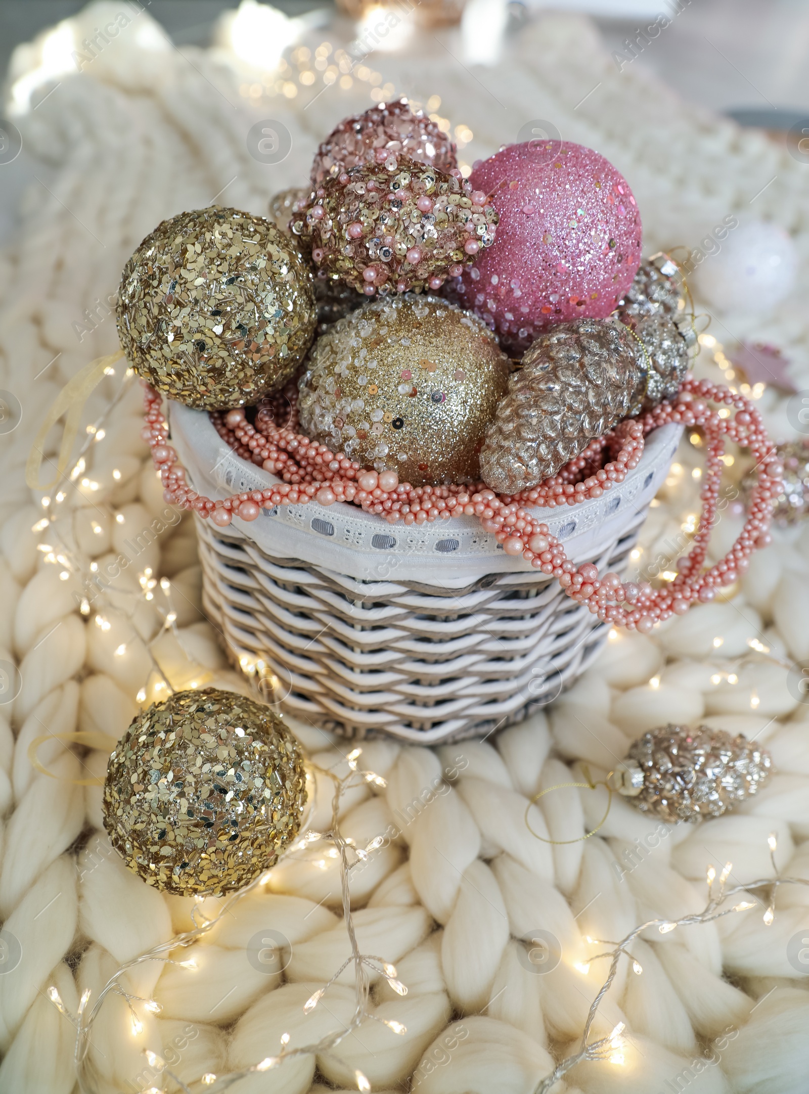 Photo of Beautiful Christmas tree baubles and fairy lights on white knitted fabric