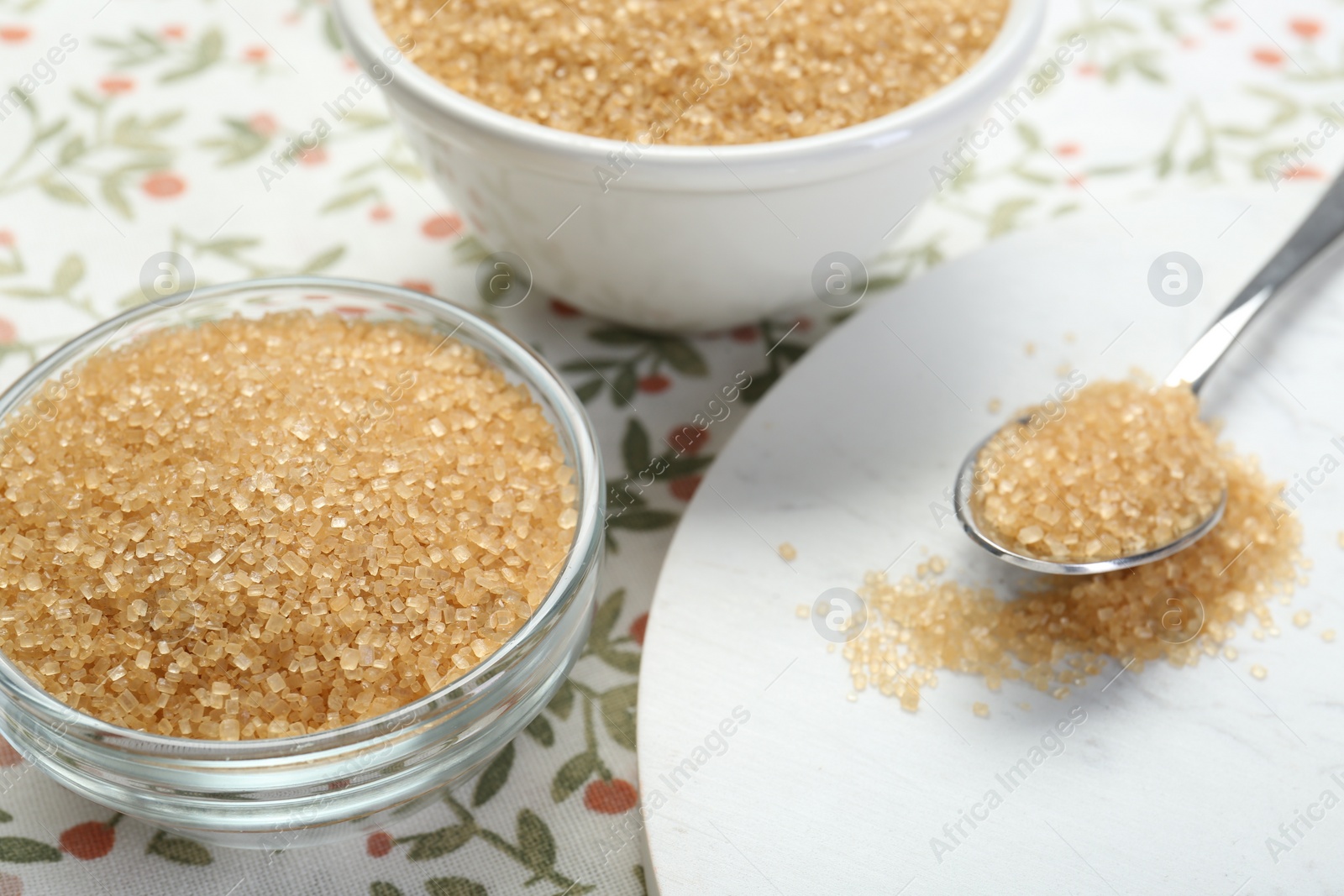 Photo of Brown sugar in bowls and spoon on table, closeup