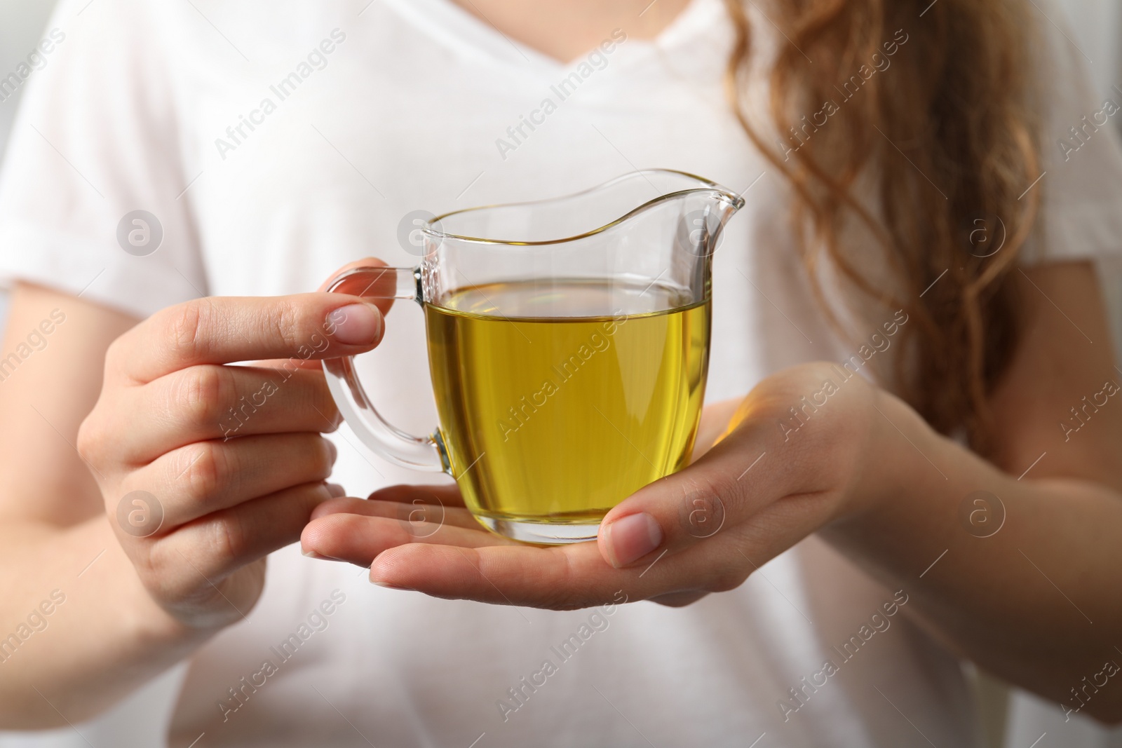 Photo of Young woman holding jug of fresh olive oil, closeup