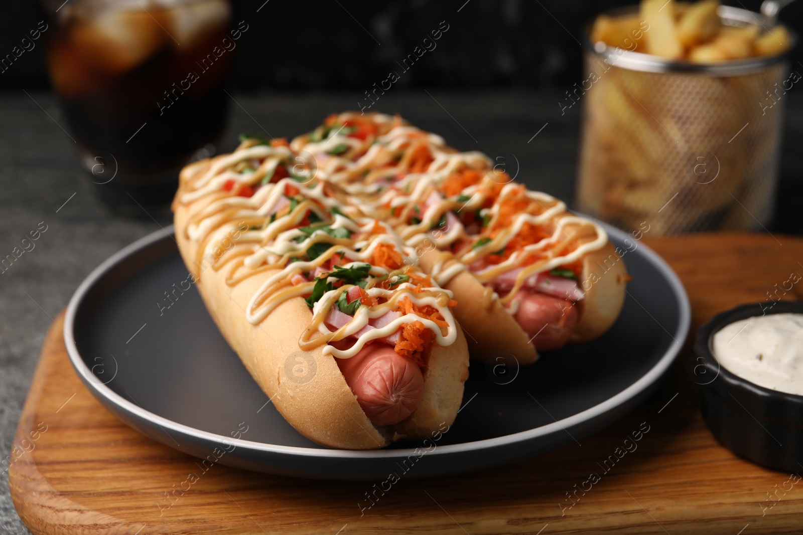 Photo of Delicious hot dogs with bacon, carrot and parsley served on table, closeup