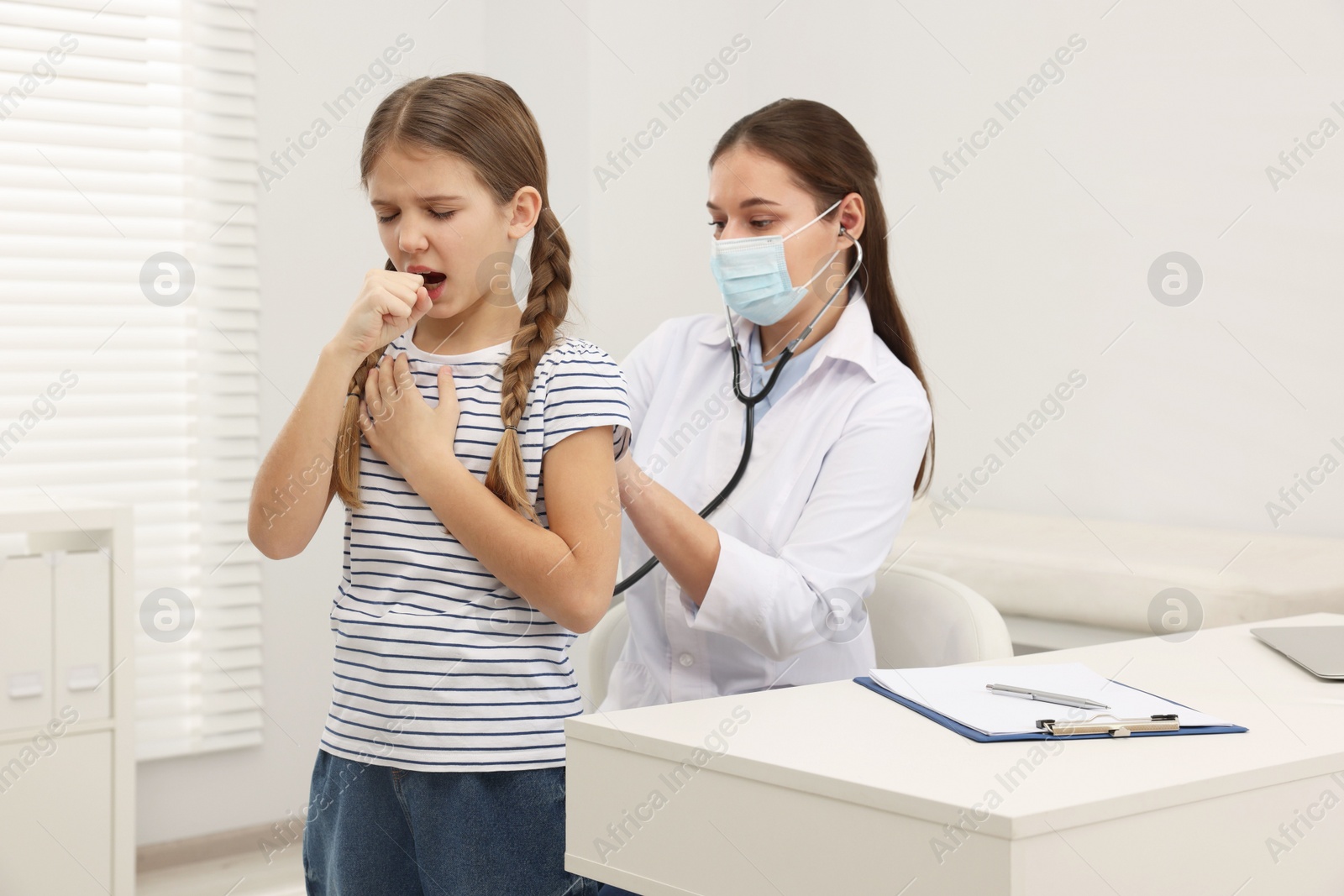 Photo of Doctor examining coughing girl in hospital. Cold symptoms