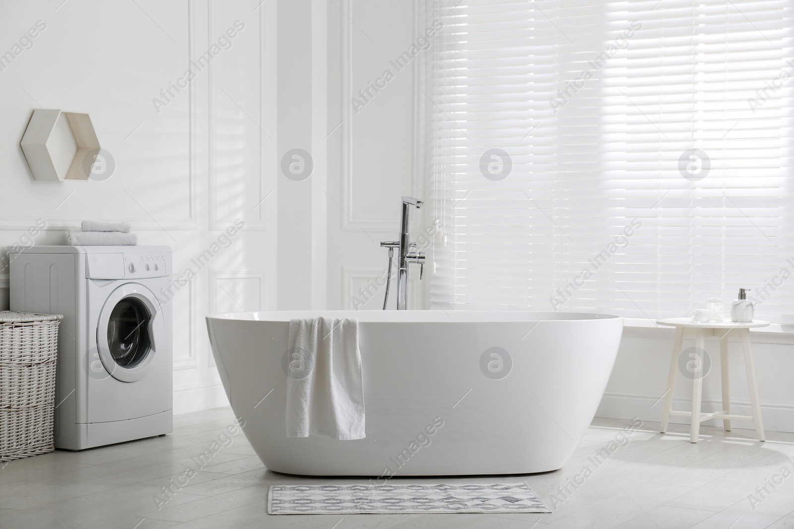 Photo of Stylish mat on floor near tub in bathroom. Interior design