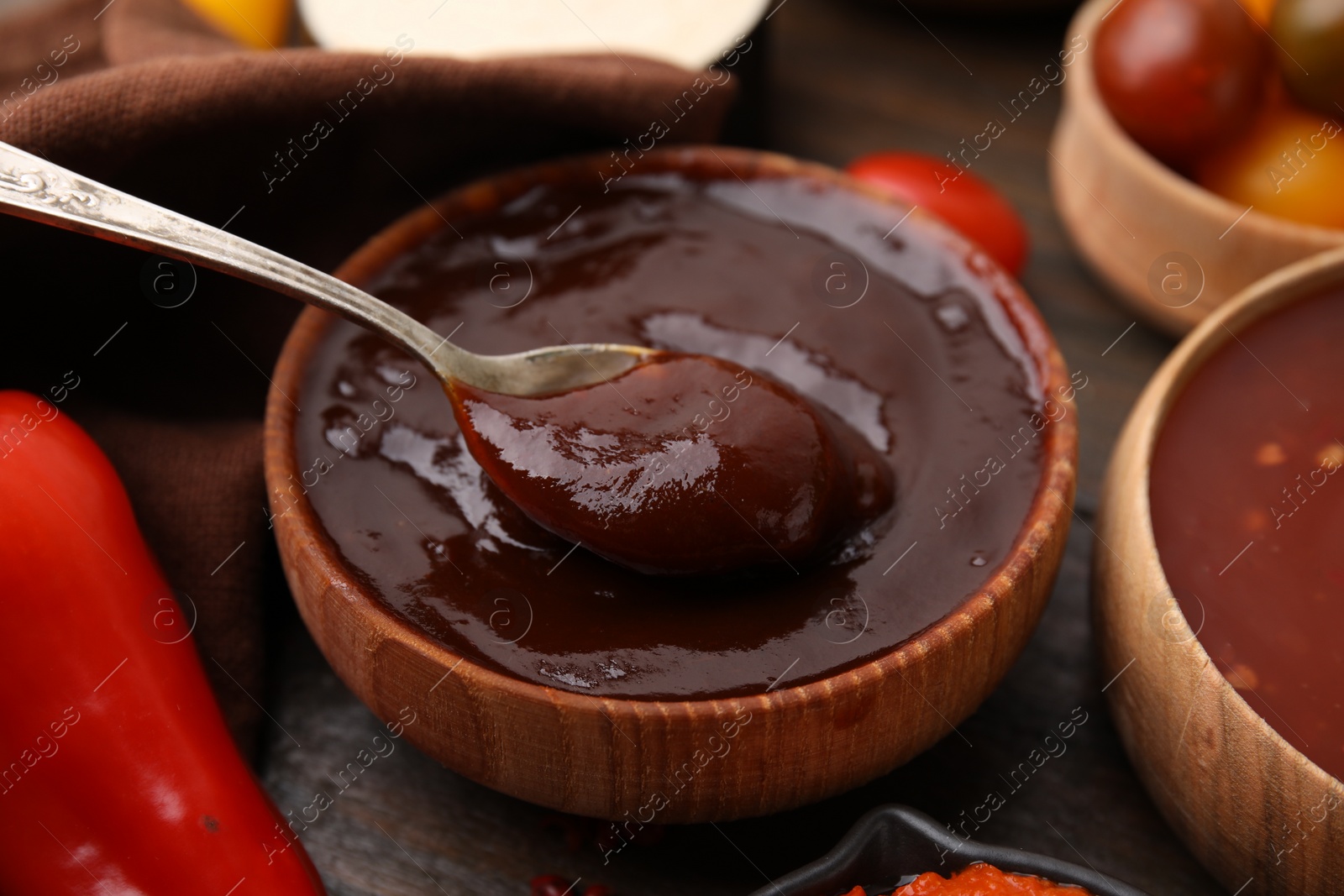 Photo of Taking homemade marinade from bowl at table, closeup