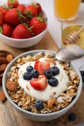 Photo of Tasty granola, yogurt and fresh berries in bowl on wooden board. Healthy breakfast