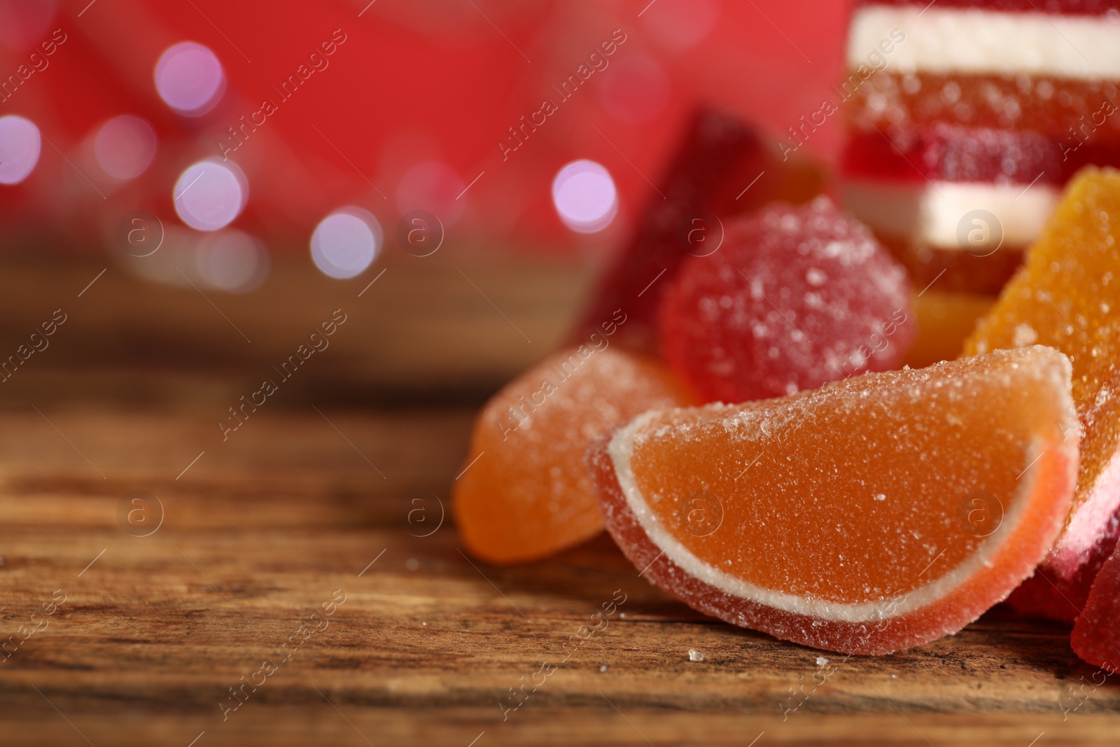 Photo of Delicious jelly candies on wooden table, closeup. Space for text