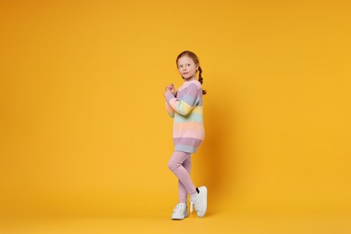 Cute little girl dancing on orange background