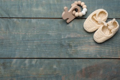 Cute baby booties and toy on light blue wooden background, flat lay. Space for text