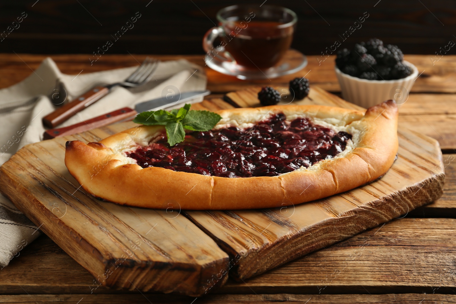 Photo of Delicious sweet cottage cheese pastry with cherry jam on wooden table