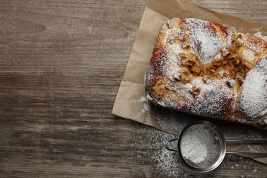Delicious yeast dough cake and strainer with powdered sugar on wooden table, flat lay. Space for text