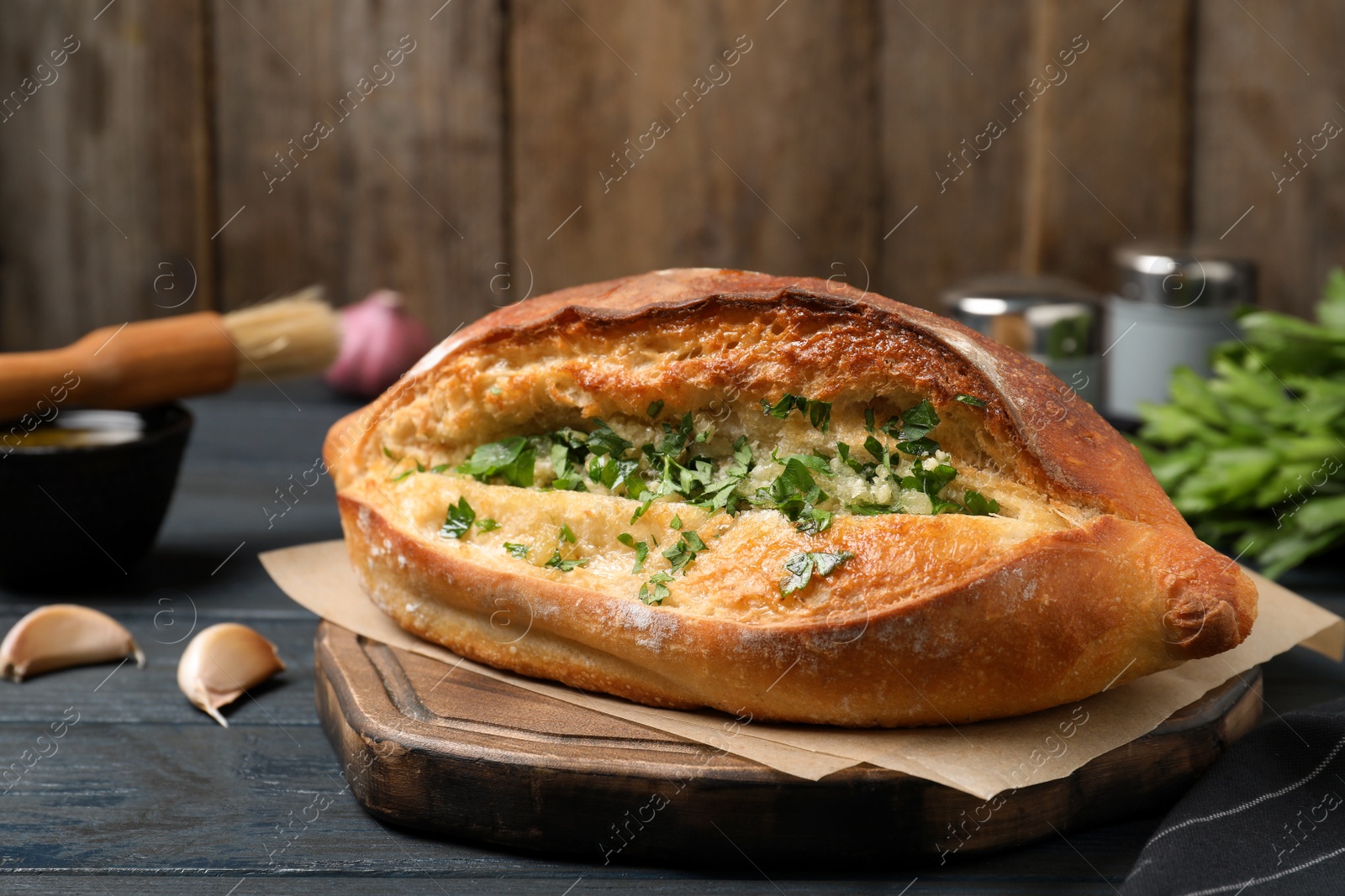 Photo of Delicious homemade garlic bread with herbs on blue wooden table