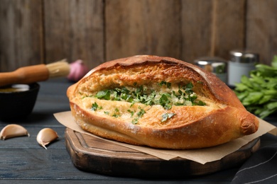 Photo of Delicious homemade garlic bread with herbs on blue wooden table