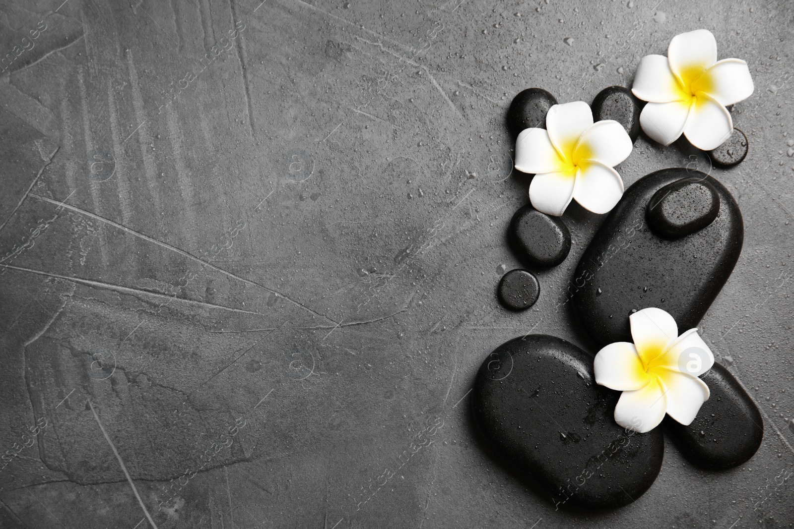 Photo of Zen stones and exotic flowers on grey background, top view with space for text