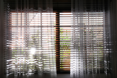 Photo of Window with beautiful curtains and blinds, closeup