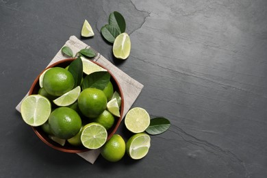 Fresh ripe limes in bowl on black table, top view. Space for text