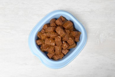 Photo of Wet pet food in feeding bowl on white table, top view