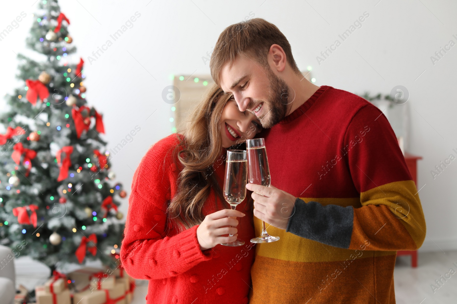 Photo of Happy young couple with glasses of champagne celebrating Christmas at home