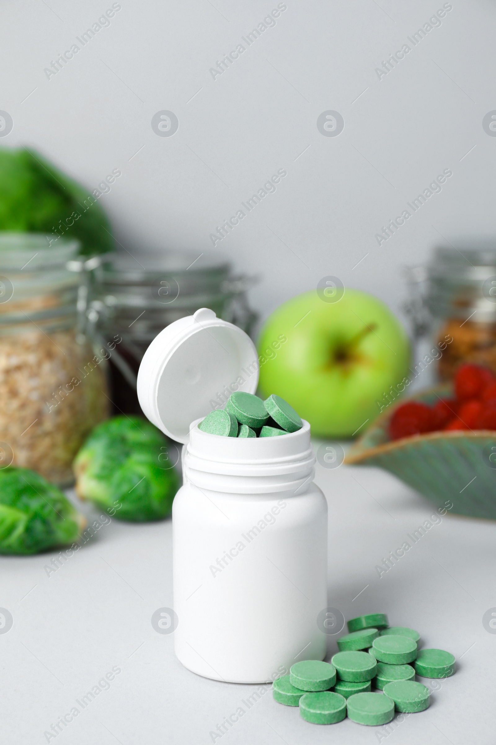 Photo of Bottle of prebiotic pills and food on grey table