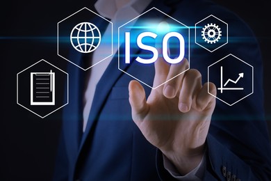 Image of Businessman pointing at virtual icon with text ISO on dark background, closeup 