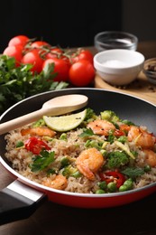 Photo of Tasty rice with shrimps and vegetables in frying pan on table