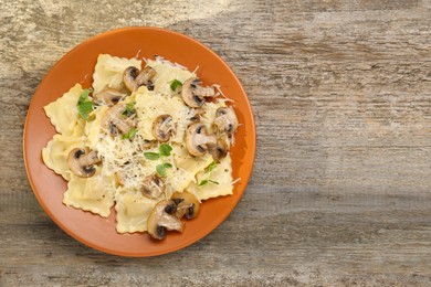 Photo of Delicious ravioli with mushrooms and cheese on wooden table, top view. Space for text