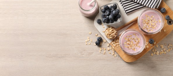 Image of Glasses of tasty blueberry smoothie with oatmeal on wooden table, flat lay with space for text. Banner design