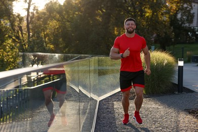 Photo of Happy man running outdoors on sunny day. Space for text