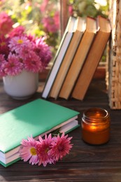 Book with beautiful chrysanthemum flowers as bookmark and candle on wooden table