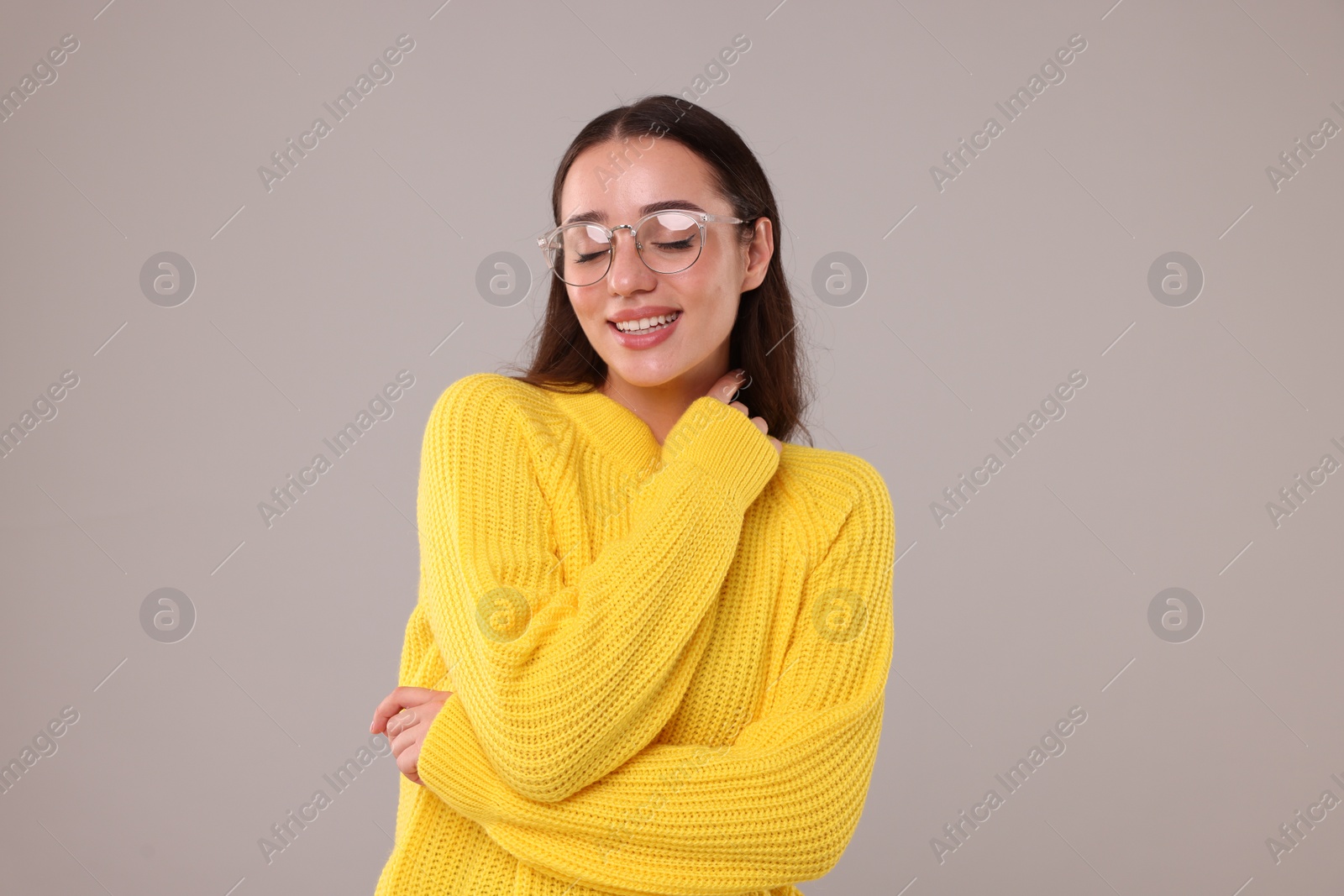 Photo of Beautiful young woman in stylish warm sweater on grey background