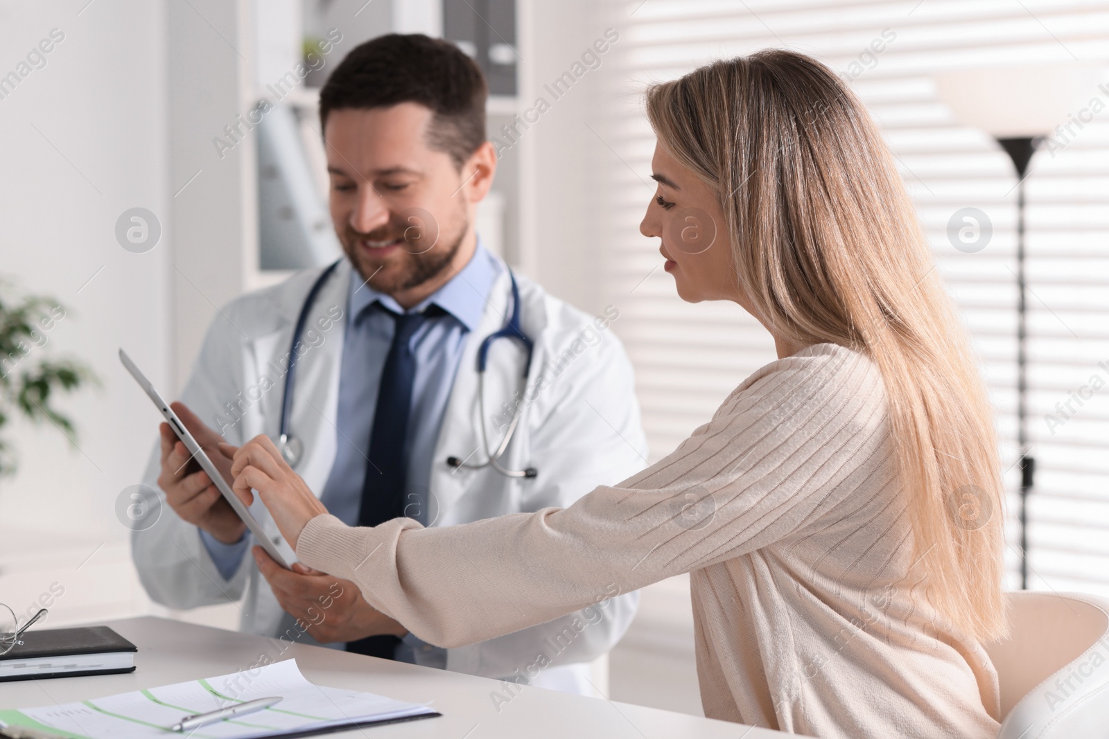 Photo of Professional doctor working with patient at white table in hospital