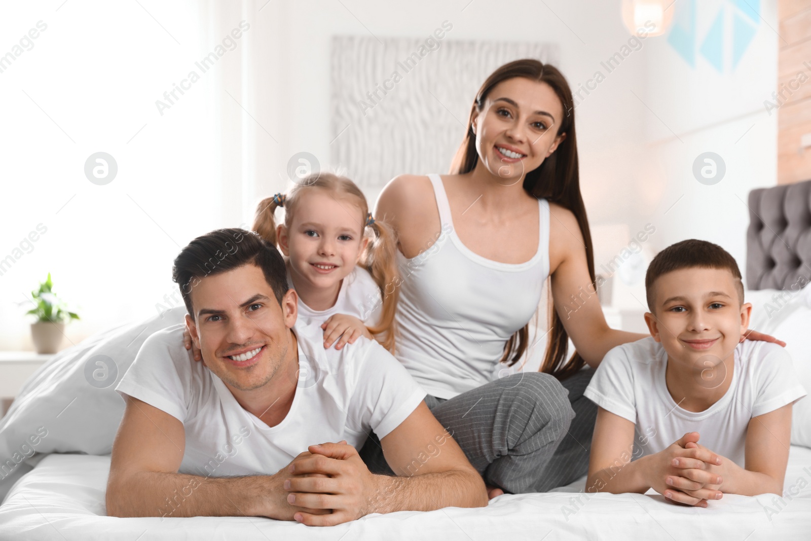 Photo of Happy young family together on large bed