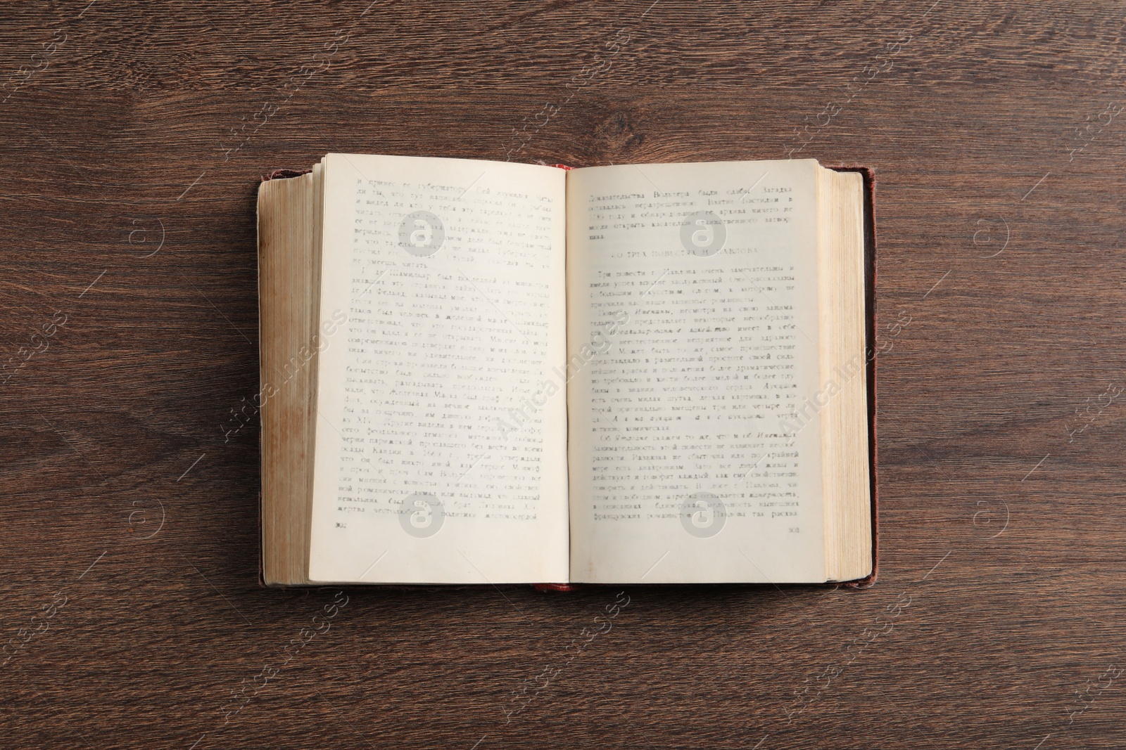 Photo of Open old hardcover book on wooden table, top view