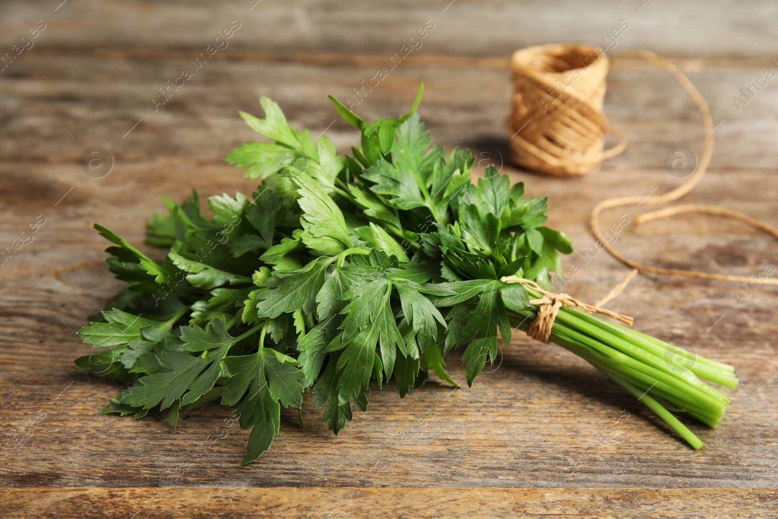 Photo of Bunch of fresh green parsley and twine on wooden table