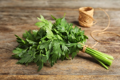 Photo of Bunch of fresh green parsley and twine on wooden table