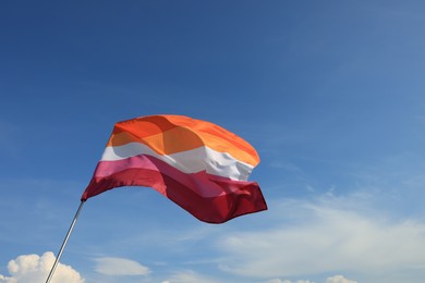 Photo of Bright lesbian flag fluttering against blue sky, low angle view. Space for text