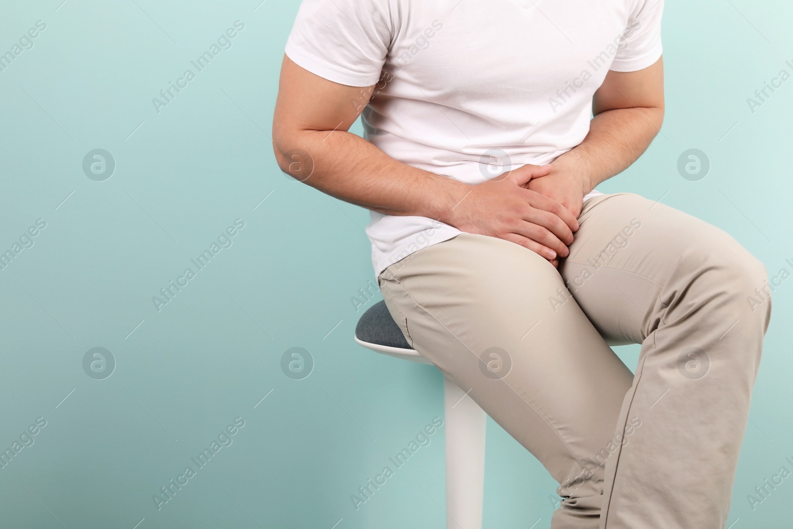 Photo of Young man with urological problems suffering from pain on color background