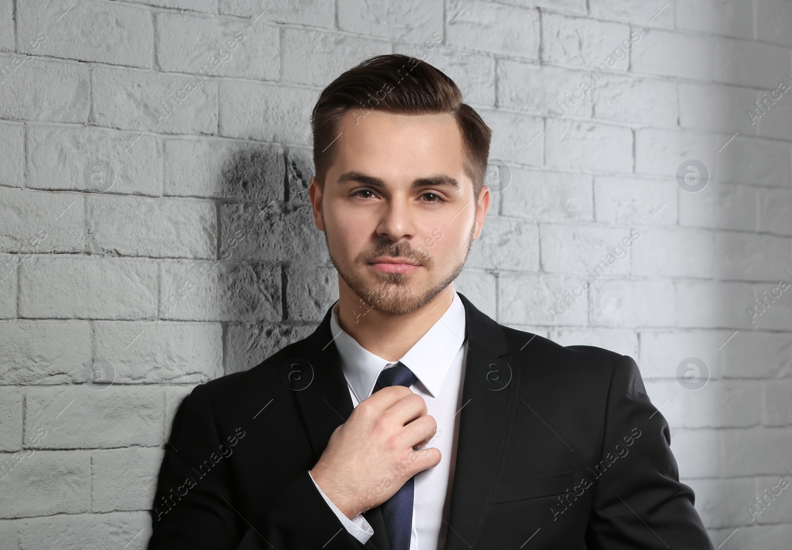 Photo of Portrait of young man with beautiful hair on brick wall background