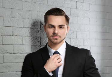 Portrait of young man with beautiful hair on brick wall background