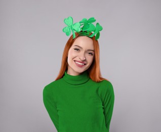 Image of St. Patrick's day party. Pretty woman with green clover headband on grey background