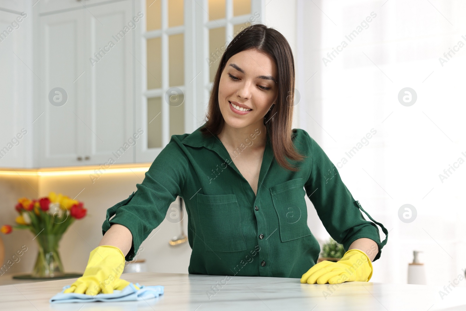 Photo of Woman cleaning table with rag in kitchen