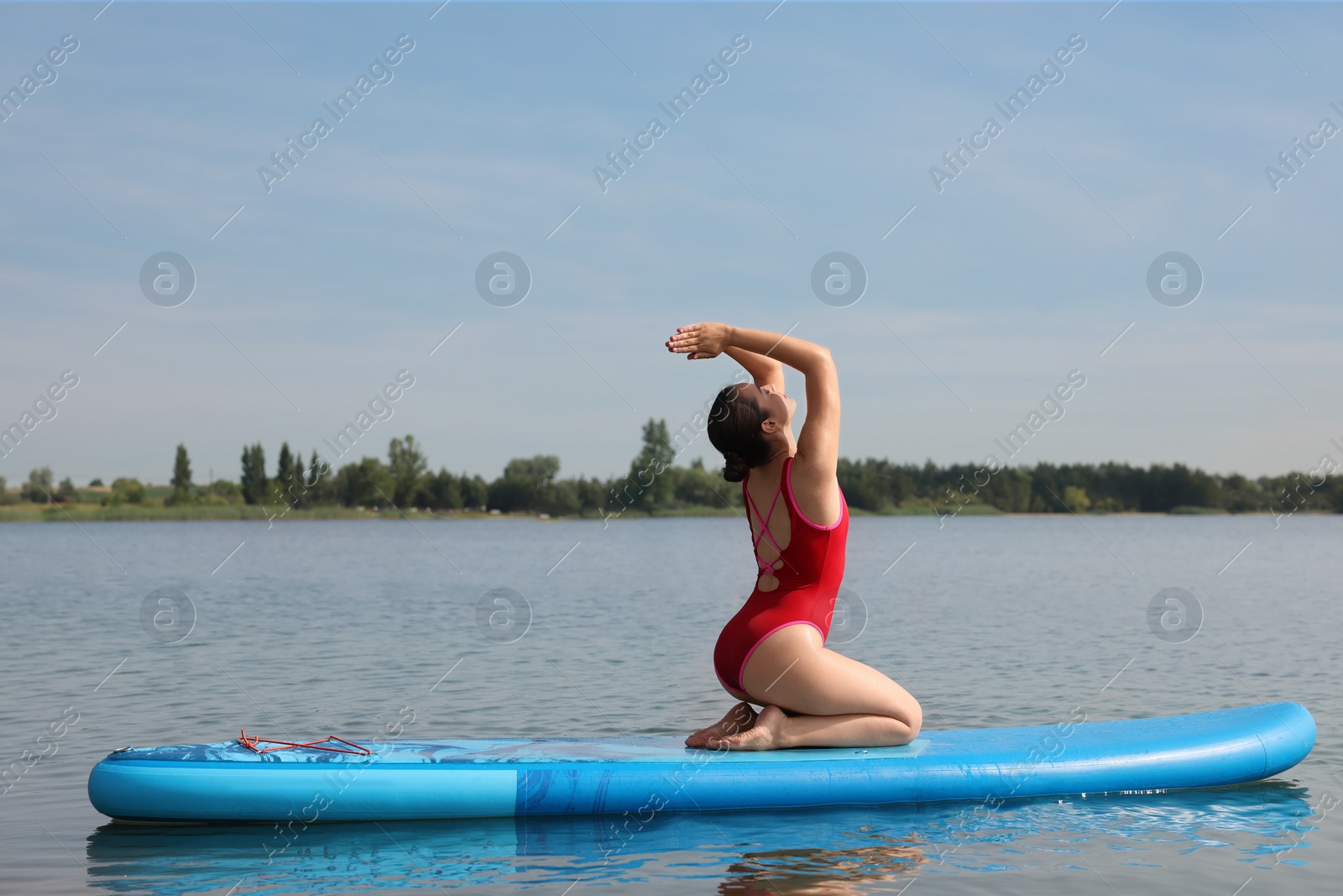 Photo of Woman practicing yoga on light blue SUP board on river