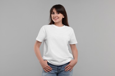 Photo of Smiling woman in white t-shirt on grey background