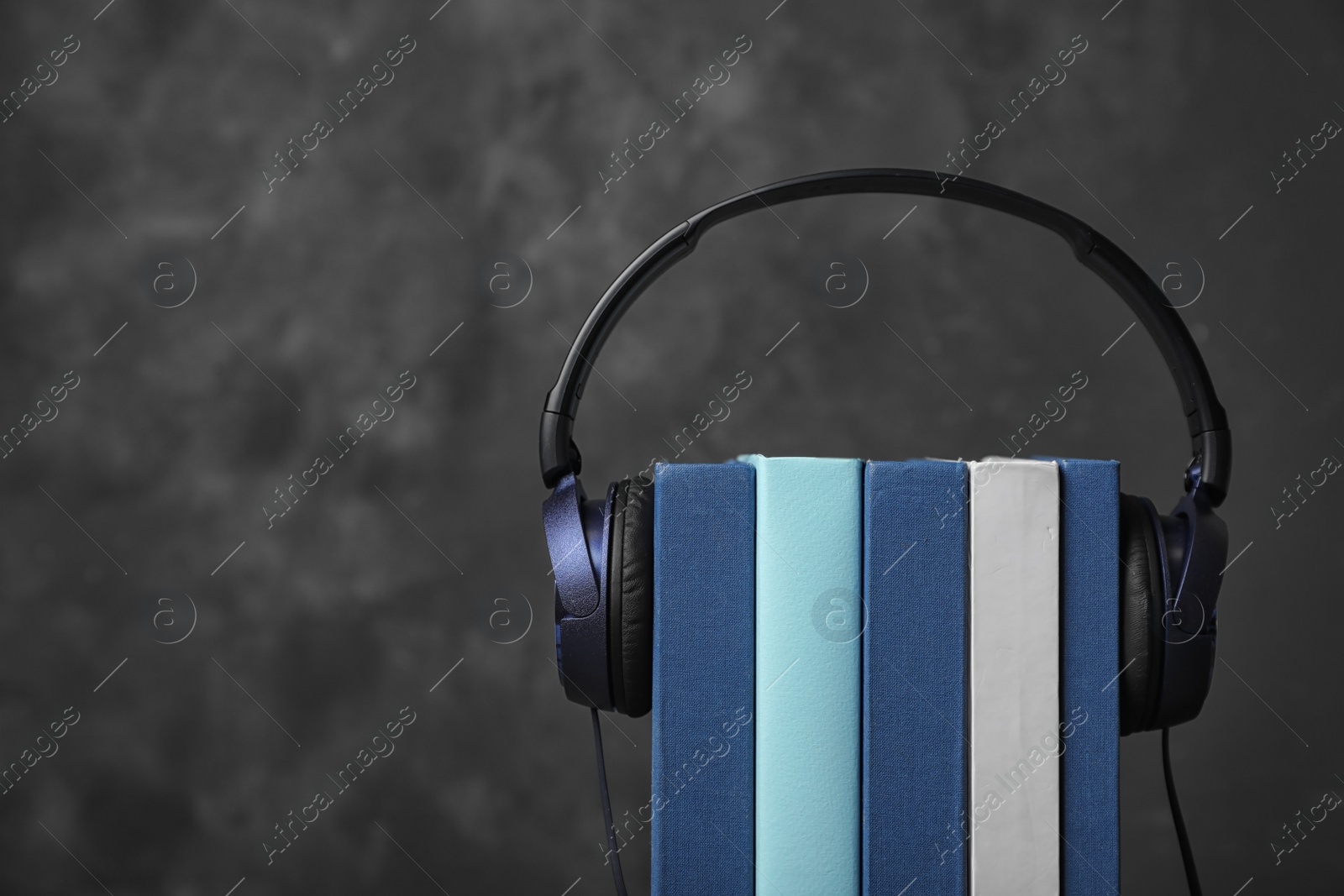 Photo of Modern headphones with hardcover books on grey background, closeup. Space for text