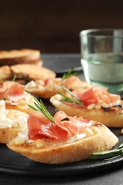 Photo of Tasty bruschettas with prosciutto and cream cheese served on table, closeup