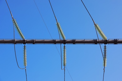 Electricity transmission power lines against blue sky, low angle view