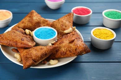 Traditional Indian food and color powders on blue wooden table. Holi festival celebration