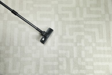 Photo of Removing dirt from white carpet with modern vacuum cleaner, top view. Space for text
