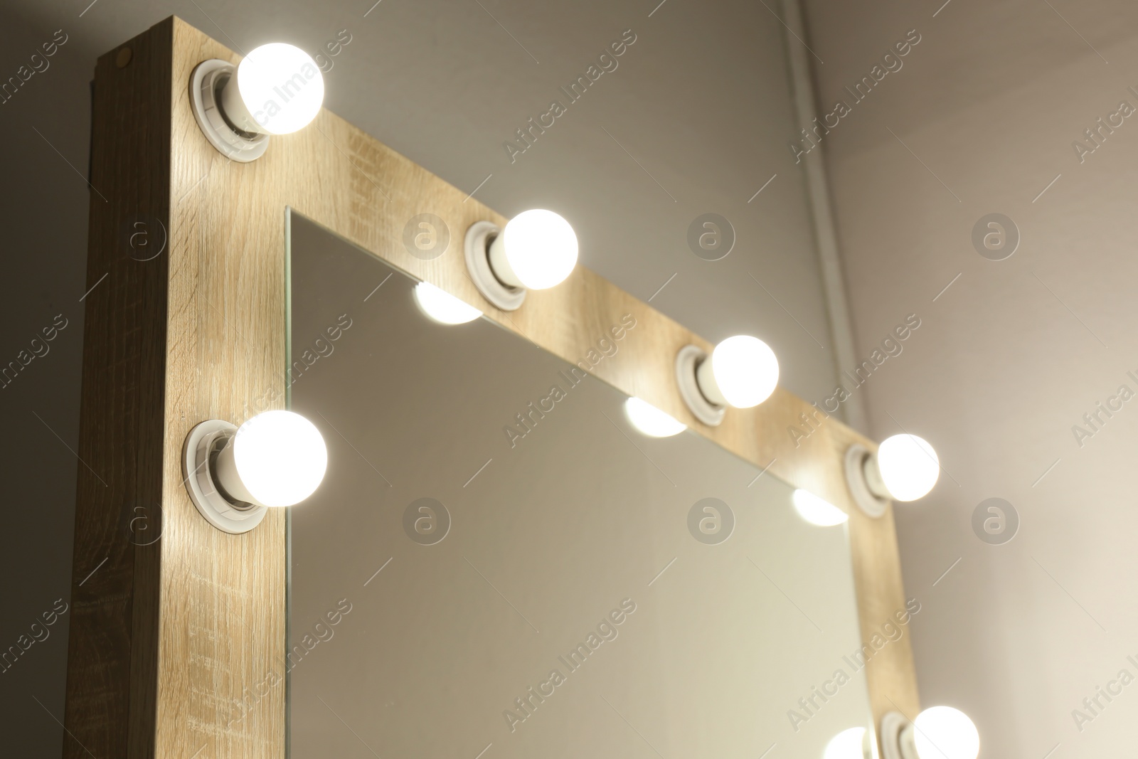 Photo of Mirror with light bulbs on white wall, closeup. Dressing room