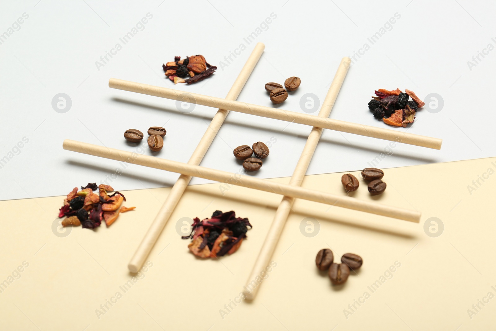 Photo of Tic tac toe game made with coffee beans and dry tea leaves on color background